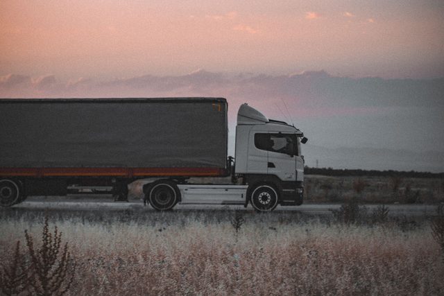 Een vrachtwagen met oplegger bij valavond