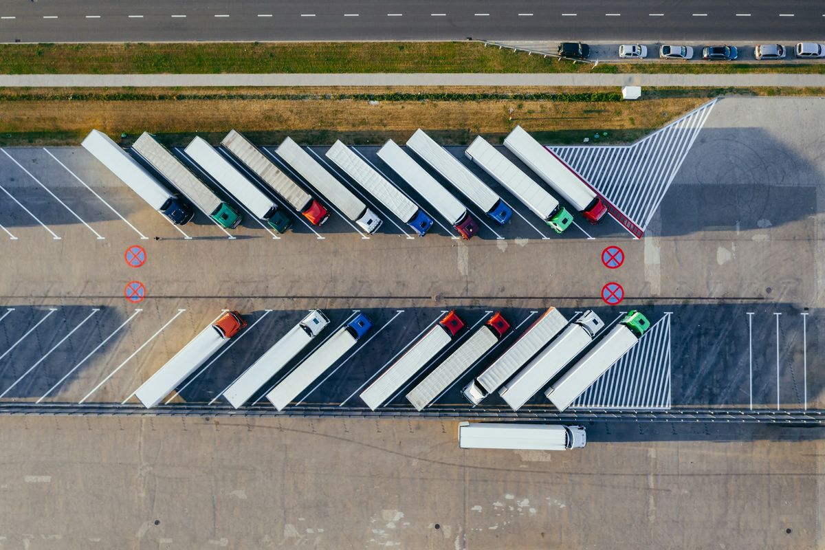 Luchtfoto van vrachtwagens met witte opleggers, schuin geparkeerd in twee rijen